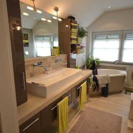 Badezimmer mit Eckbadewanner, modernem Waschbecken und beleuchteten Spiegel